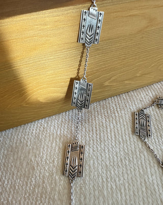 Silver chain with geometric links on a wooden surface