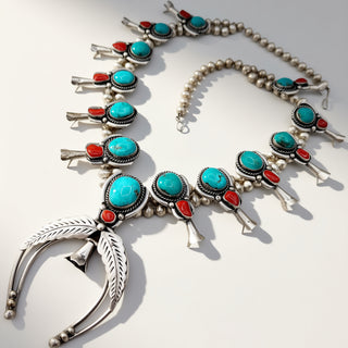 Silver necklace with turquoise and red stones on a white background