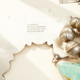 Close-up of a piece of jewelry with turquoise stone and gold accents on a light background.