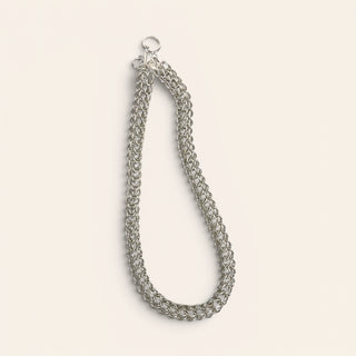 Silver chain necklace on a light beige background