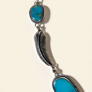 Necklace with turquoise stones and feather design on a beige background