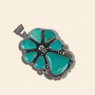 Turquoise pendant with silver setting on a beige background