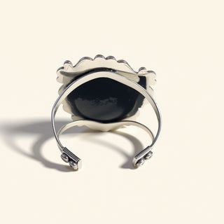 Silver ring with a black stone on a beige background