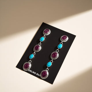 Pair of earrings with gemstones on a black card labeled 'Sterling Silver'.