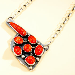 Necklace with a silver and red pendant on a beige background