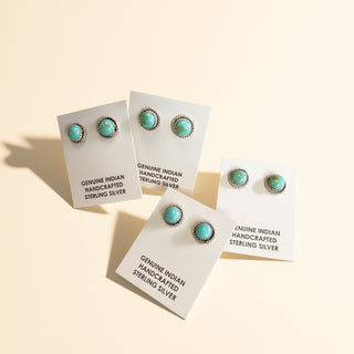 Pairs of silver earrings with turquoise stones on a beige background