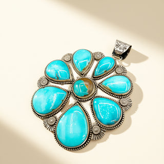 Turquoise stone pendant with silver setting on a beige background
