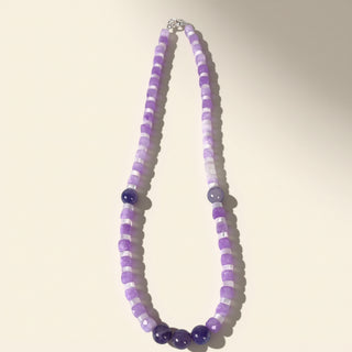 Necklace with purple and white beads on a light background