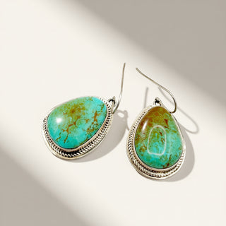 Turquoise stone earrings with silver settings on a light background