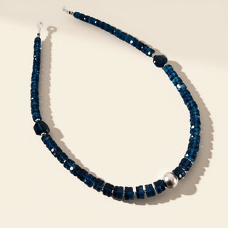 Blue beaded necklace with a silver clasp on a beige background