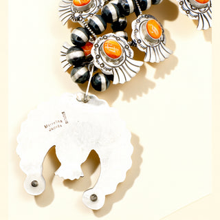 Beaded necklace with orange and black beads on a beige background