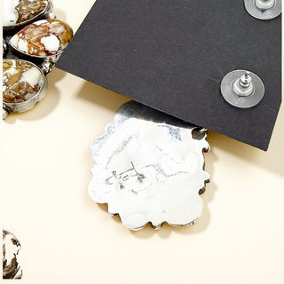 Close-up of a silver earring with a black card on a beige surface