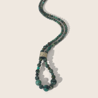 Beaded necklace with green and black beads on a light background