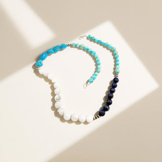 Blue and white necklace with black pearls on a beige background