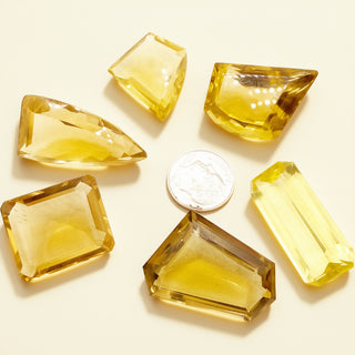 Yellow gemstones of various shapes and sizes on a light background