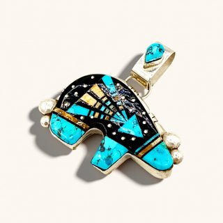 A Southwestern-style turquoise and black inlay pendant photographed on a clean off-white background.