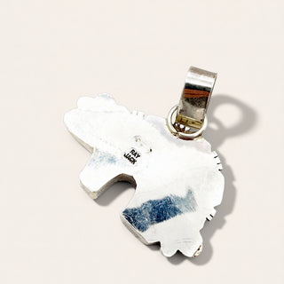 A sterling silver pendant shaped like a stylized animal head with a polished bail, shown on a warm off-white background. 
