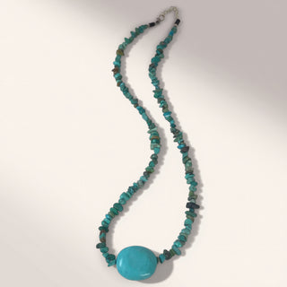 Turquoise beaded necklace with a large turquoise stone on a white background