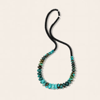 Necklace with black and turquoise beads on a beige background