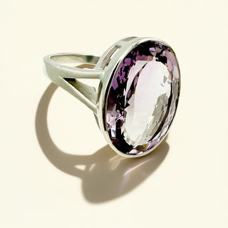 Silver ring with a large purple gemstone on a beige background