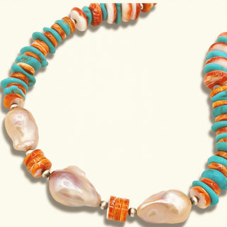 Necklace with pearls and orange and turquoise flat beads on a beige background