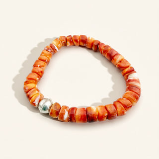Beaded bracelet with orange and white beads on a light background