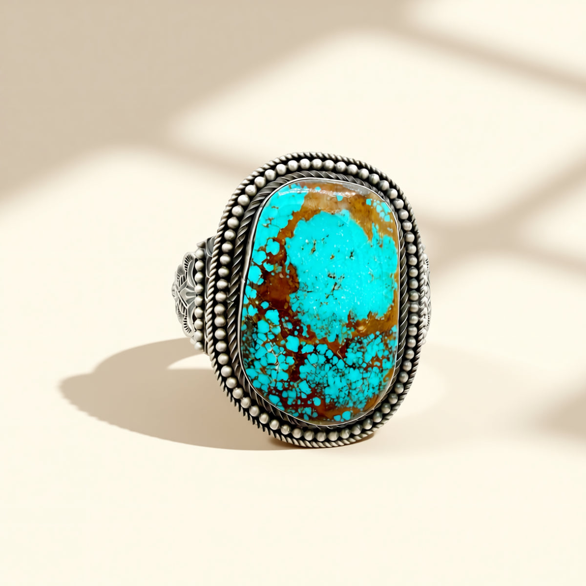 Turquoise cuff with silver band on a beige background