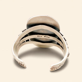 Silver bracelet with intricate design on a beige background
