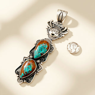 Silver pendant with turquoise stones next to a coin on a beige background