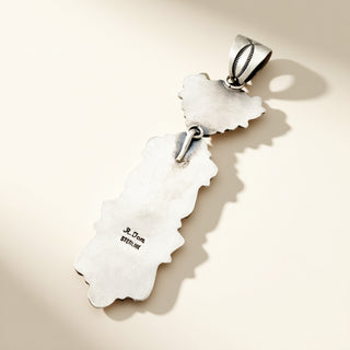 Silver pendant with 'R. Tom' engraving on a beige background