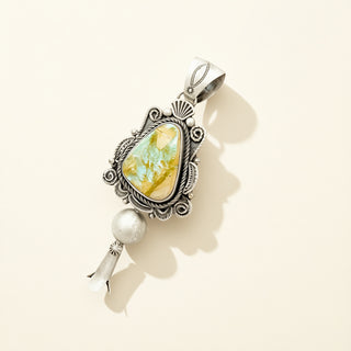 Silver pendant with a yellow gemstone and pearl on a beige background