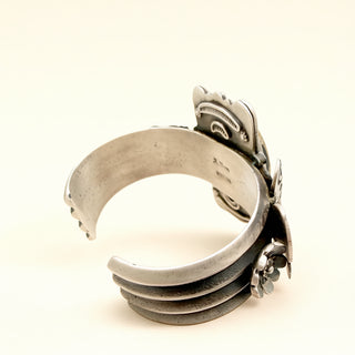 Silver cuff with intricate design on a white background