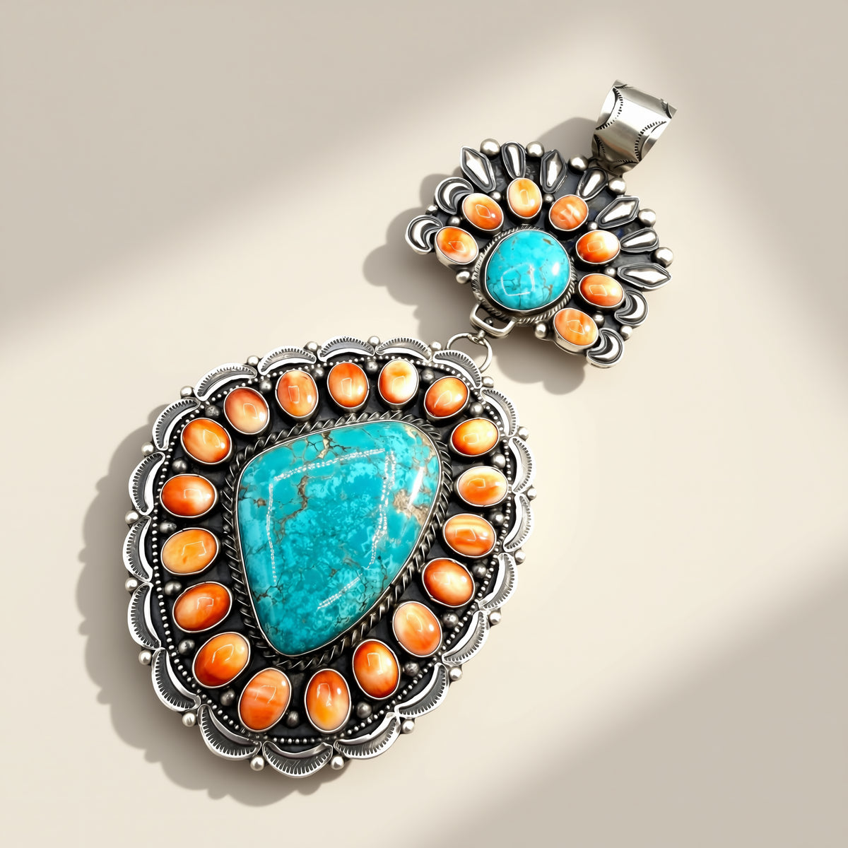Two turquoise and orange stone pendant on a beige background