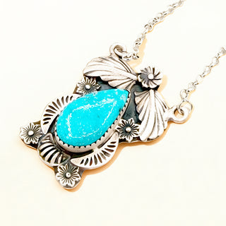 Turquoise pendant necklace with silver leaf designs on a white background
