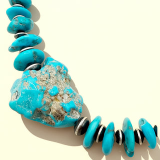 Turquoise necklace with a large turquoise stone on a beige background