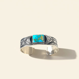Silver bracelet with a turquoise stone on a beige background