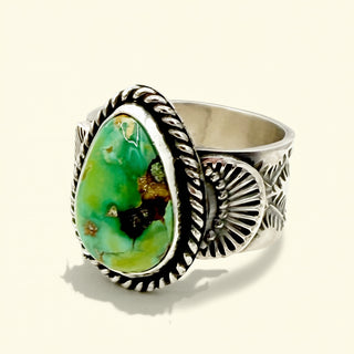 Silver ring with a green stone on a beige background