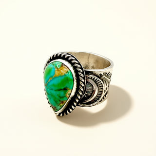 Silver ring with a green stone on a beige background