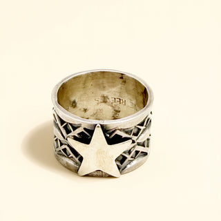 Silver ring with star design on a beige background