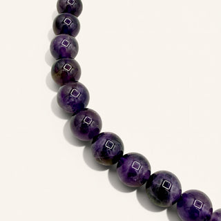 purple beaded jewelry on a beige background