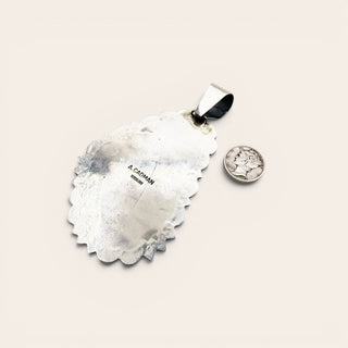 Silver pendants on a light beige background, stamped A. Cadman