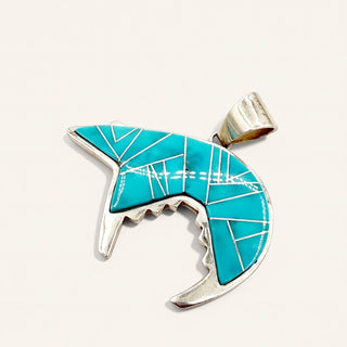 silver pendant with turquoise stone in curved shaped on a beige background