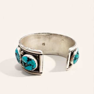 sterling silver cuff with turquoise stones on a beige background