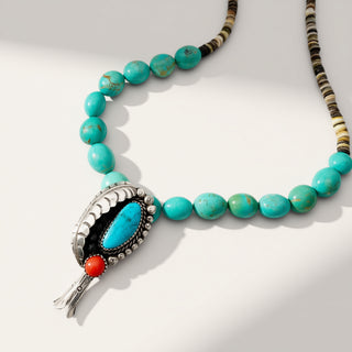 Turquoise beaded necklace with a decorative pendant on a white background