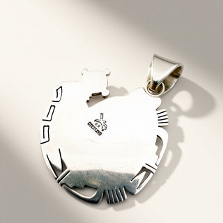 A sterling silver pendant shaped like a stylized animal head with cutout details, shown on a light beige background with a soft shadow. The pendant features a polished finish and a small 'sterling' hallmark stamped on the side.