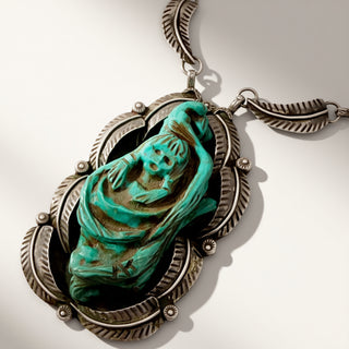 Turquoise stone pendant on a silver chain against a white background