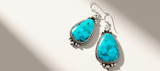 turquoise earrings on a beige background banner
