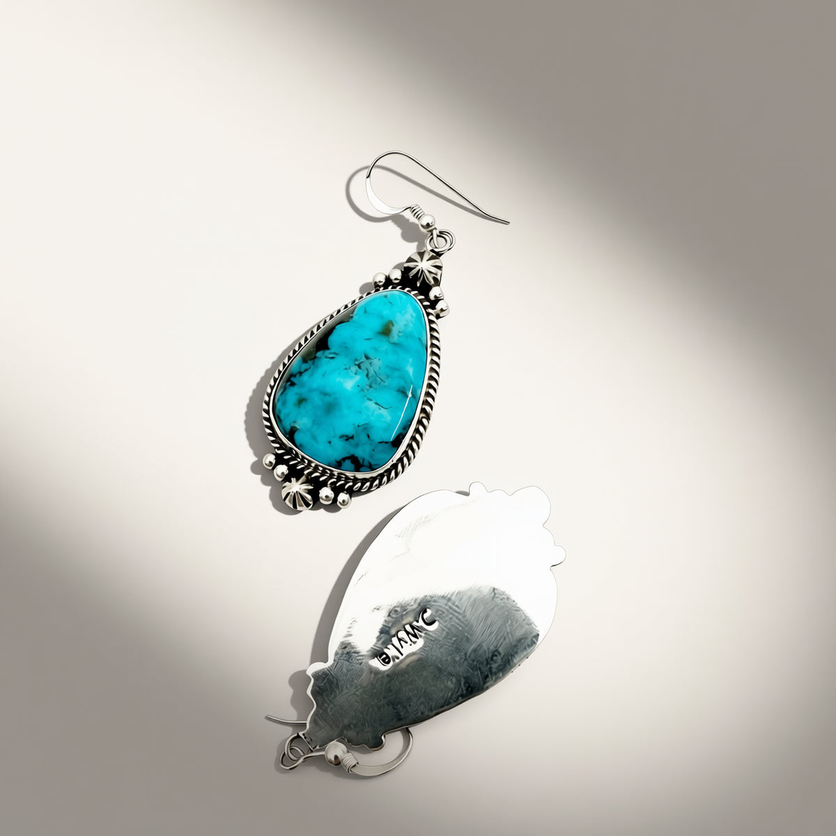 turquoise and silver earring on a beige background
