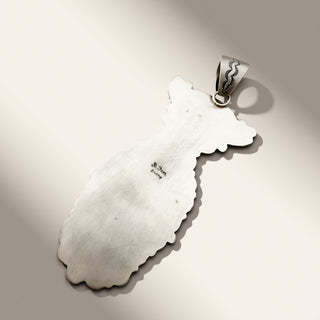 silver pendant with 'R. Tom Sterling' engraved on a beige background