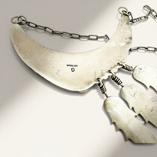 Sterling silver crescent moon pendant necklace with dangling bat-shaped charms and a chain link back, shown on a light gray background.